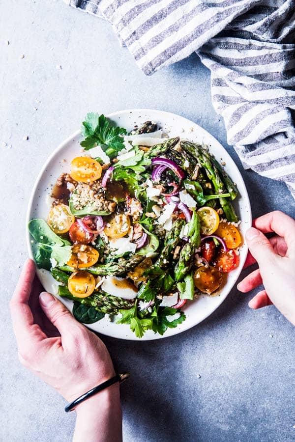 Putting a plate go Quinoa Spinach Salad with Asparagus on the table.