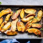 Roasted Fingerling Potatoes on a sheet pan with fresh parsley, next to a blue napkin.