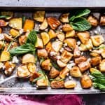 Roasted red potatoes with feta and mint on a baking sheet with a pink napkin.