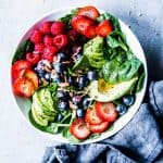 Spinach Avocado Salad in a white bowl with a dark napkin next to it.