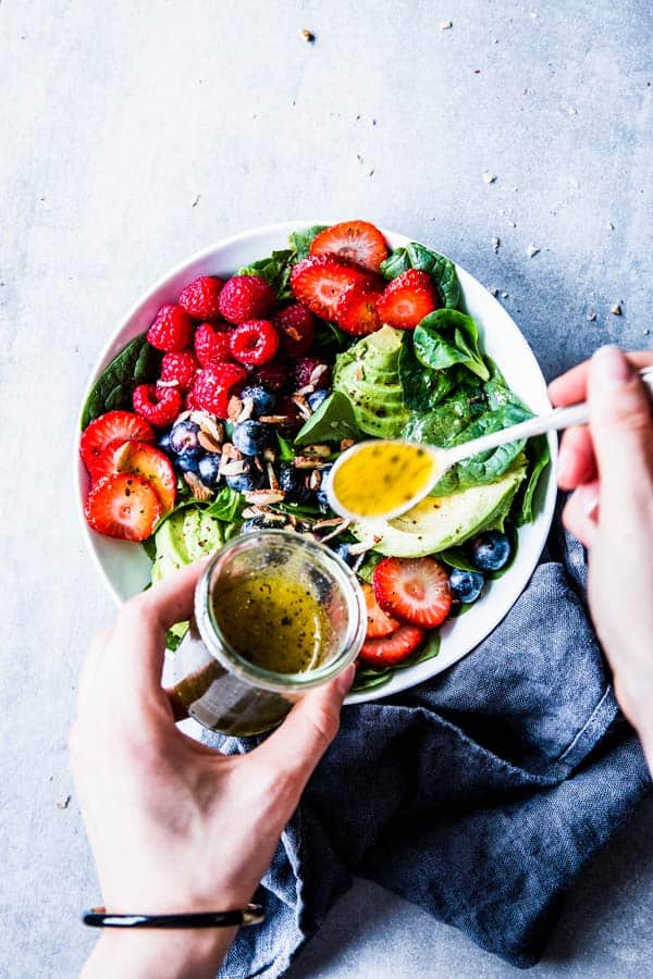 Spooning white balsamic vinaigrette over Spinach Avocado Salad.