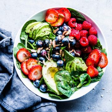 Spinach Avocado Salad in a white bowl with a black napkin.