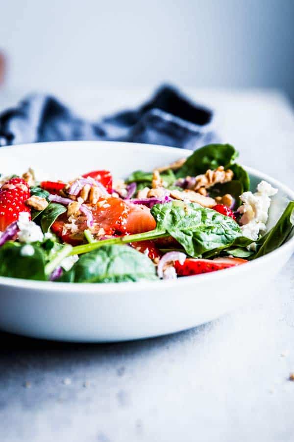 Spinach Strawberry Walnut Salad in a white bowl on the table.