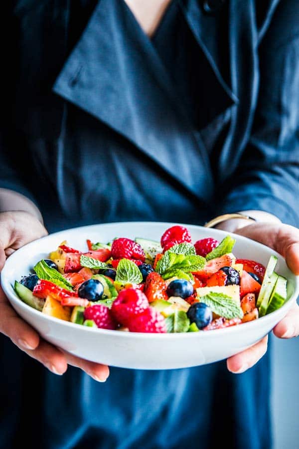 Woman holding a bowl of summer fruit salad.