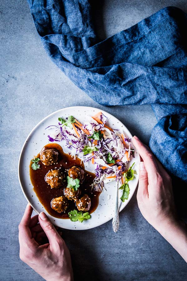 Serving a plate of teriyaki meatballs and coleslaw.