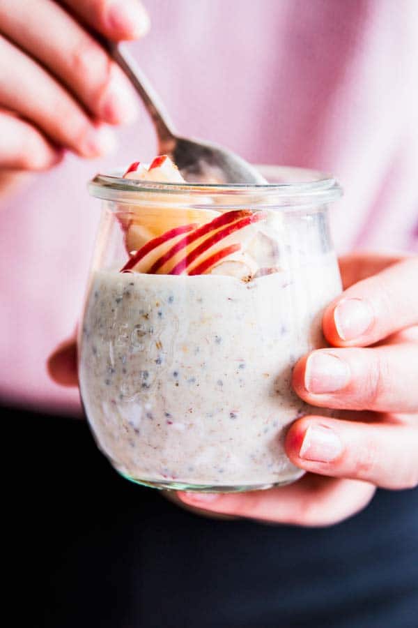 woman holding a jar with apple cinnamon overnight oats