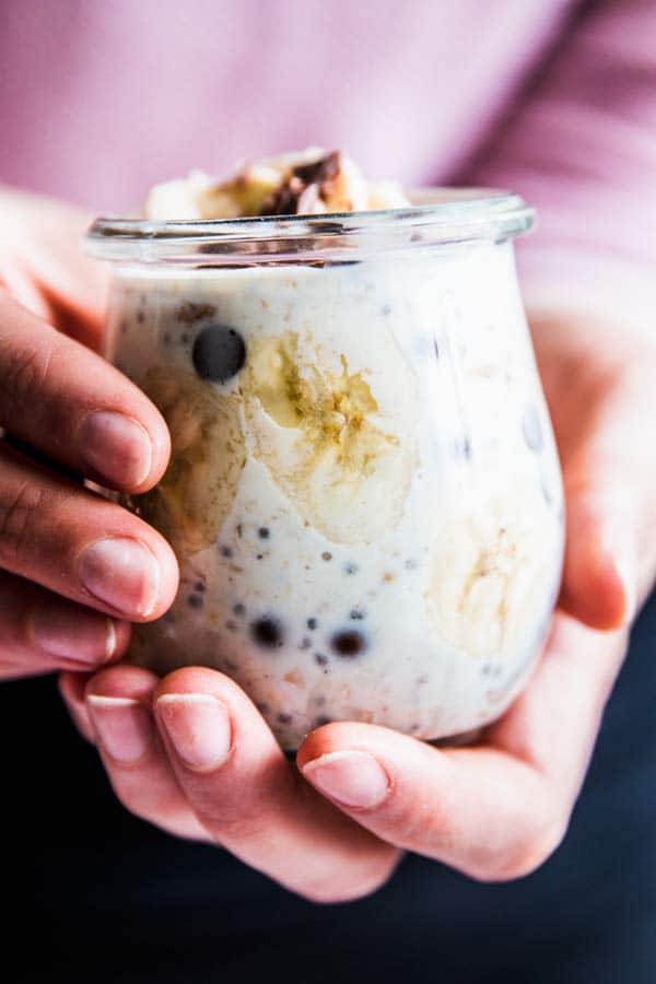 Woman holding a jar of banana chocolate chip overnight oats.