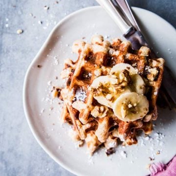 Banana Nut Waffles on a white plate with cutlery and a pink napkin.