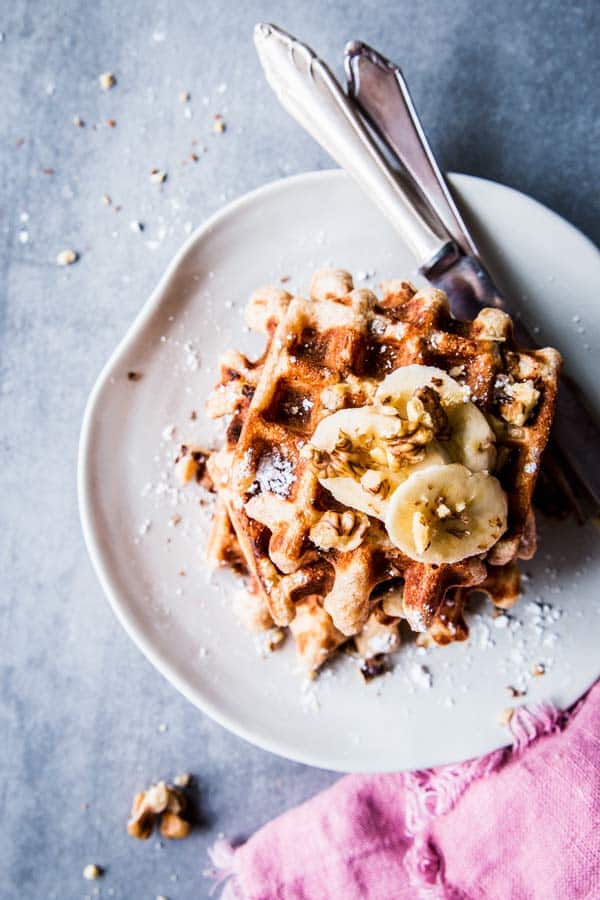 Banana Nut Waffles on a white plate with cutlery and a pink napkin.