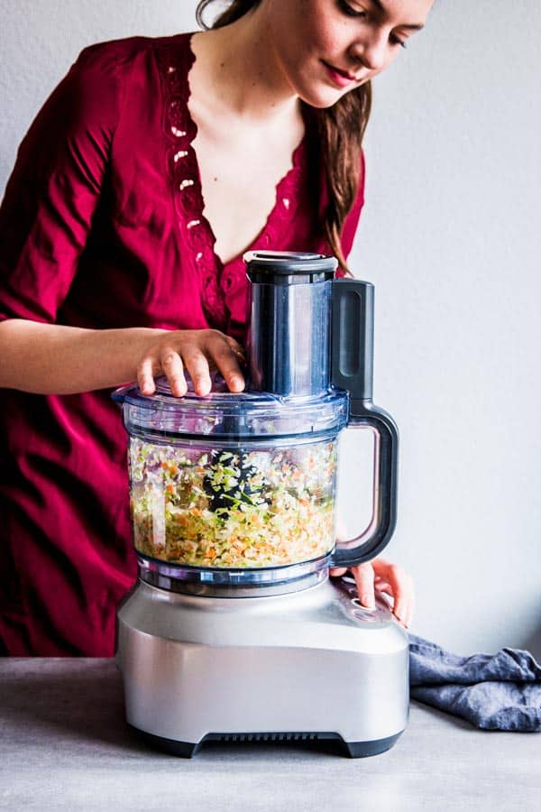 Woman chopping vegetables in a foodProcessor to make bbq turkey meatloaf