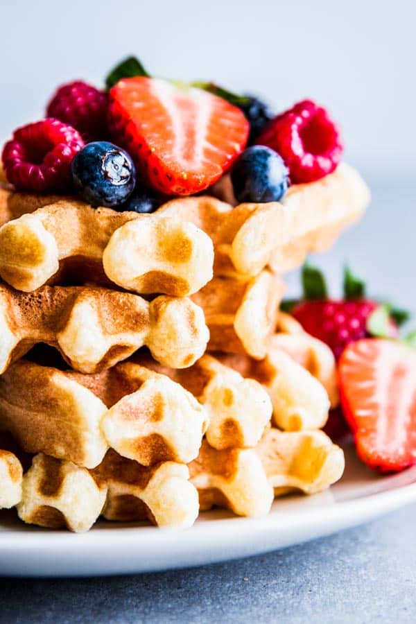 Close up photo of fluffy buttermilk waffles with berries.