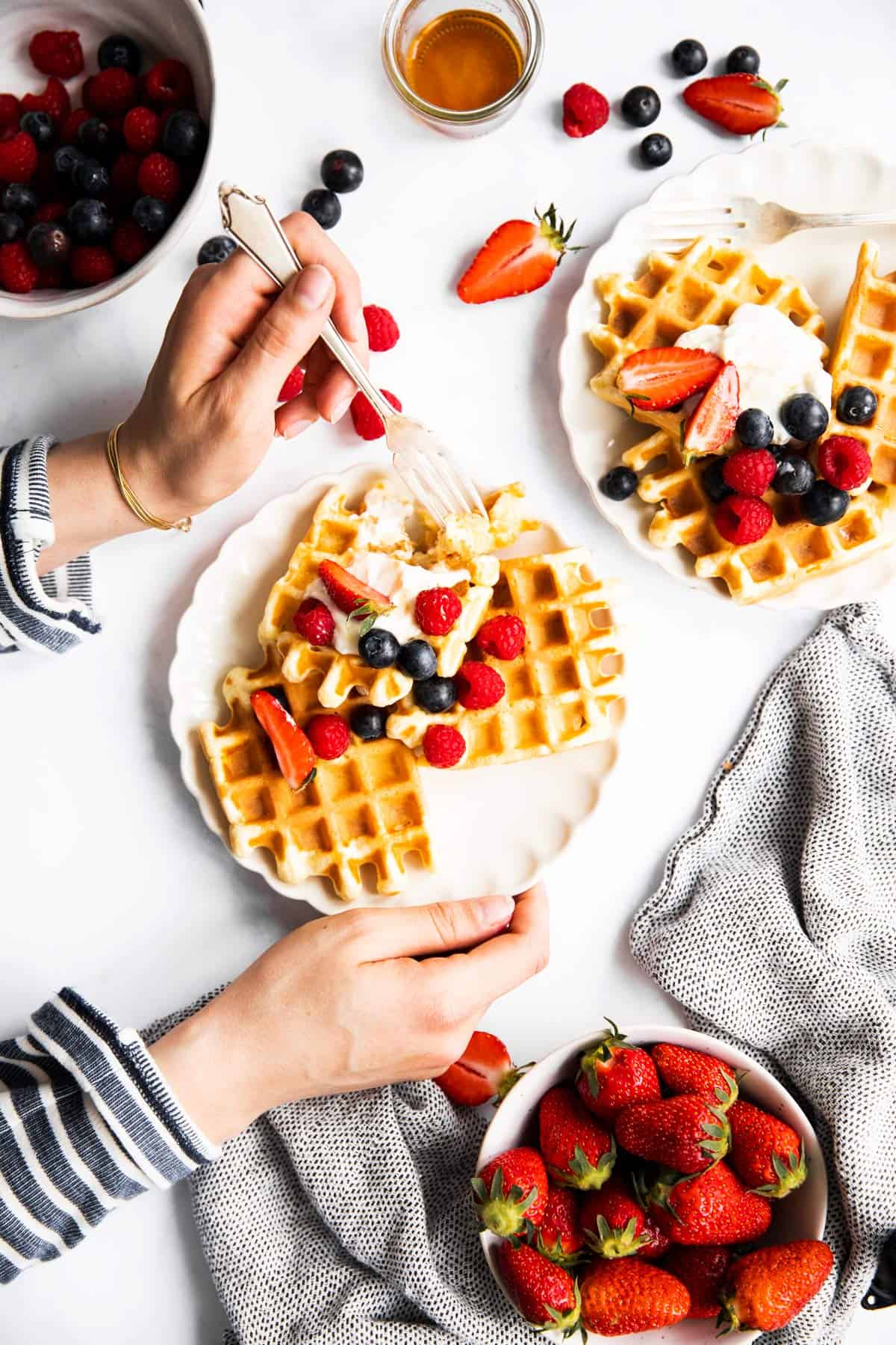 female hands holding plate with waffles and berries