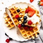 top down view on plate of buttermilk waffles garnished with berries and cream
