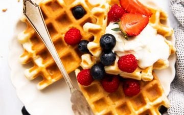 top down view on plate of buttermilk waffles garnished with berries and cream