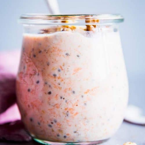 Carrot Cake Overnight Oats in a glass jar with a spoon.