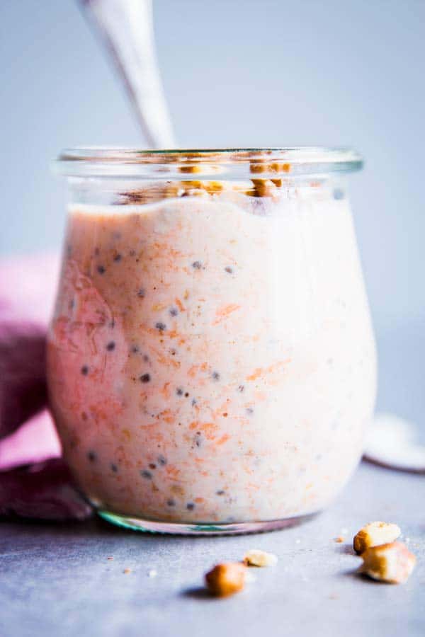 Carrot Cake Overnight Oats in a glass jar with a spoon.