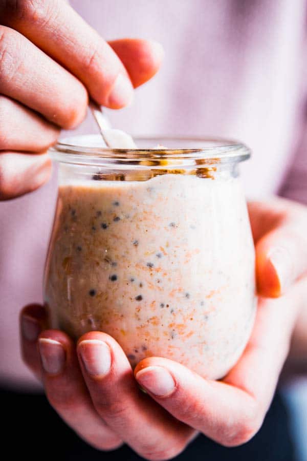 Woman holding a jar of carrot cake overnight oats.