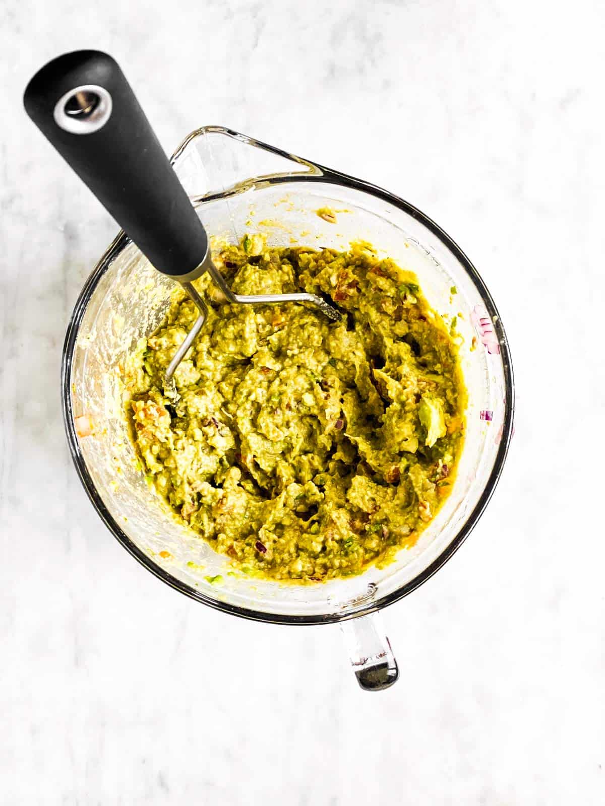 mashed guacamole in glass bowl