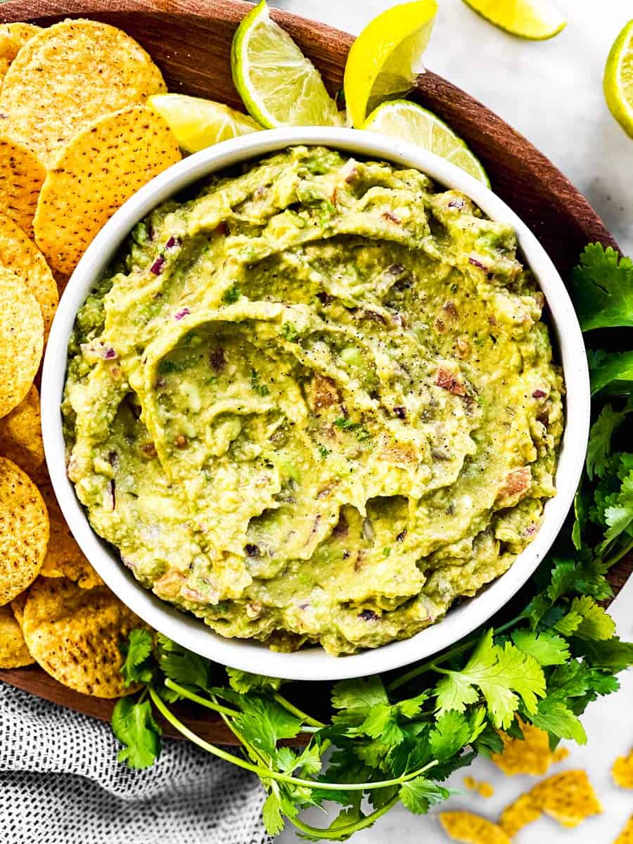 overhead view of bowl with guacamole on platter with corn chips