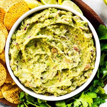 overhead view of bowl with guacamole on platter with corn chips