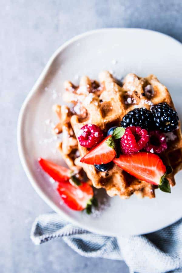 Fluffy Whole Wheat Waffles on a white plate with fresh berries.