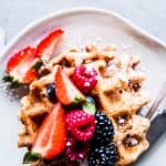 Fluffy Whole Wheat Waffles on a white plate with berries.