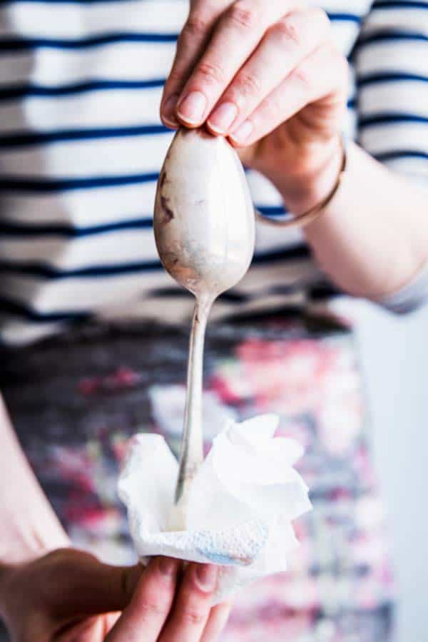 Woman in a stripe shirt wrapping a spoon handle in a paper towel.