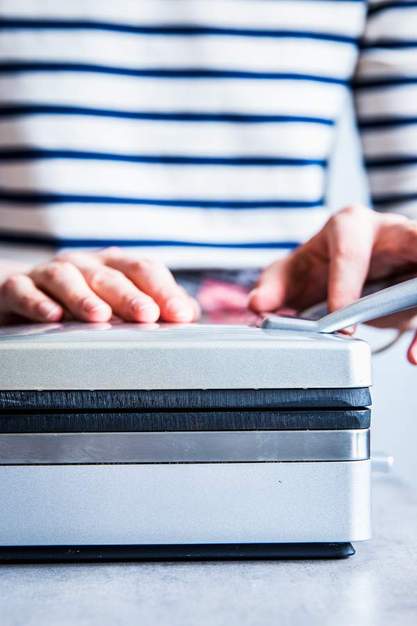 Woman in a striped top with a waffle iron.