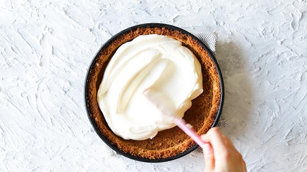 spreading cheesecake filling in a graham cracker crust for no bake strawberry pie