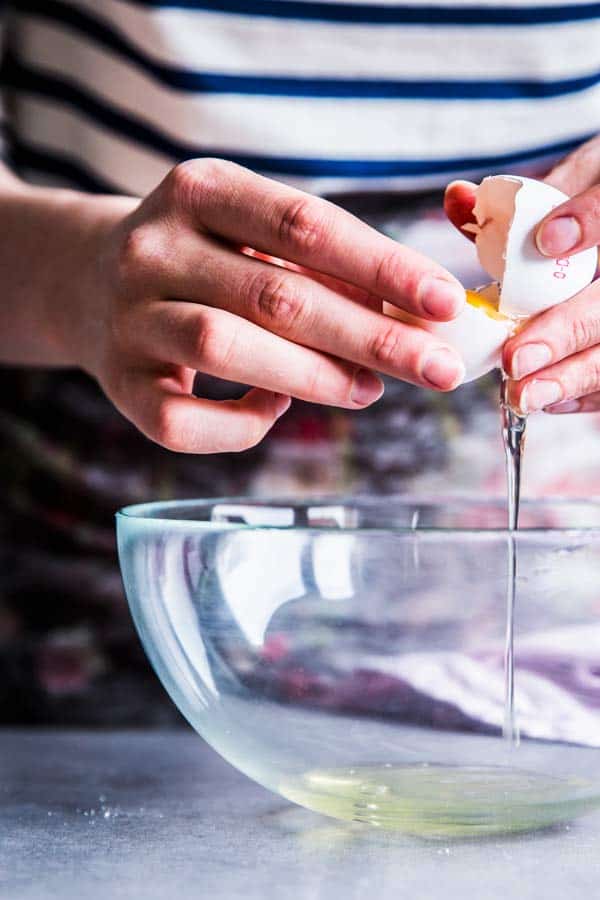 Woman opening a raw egg.