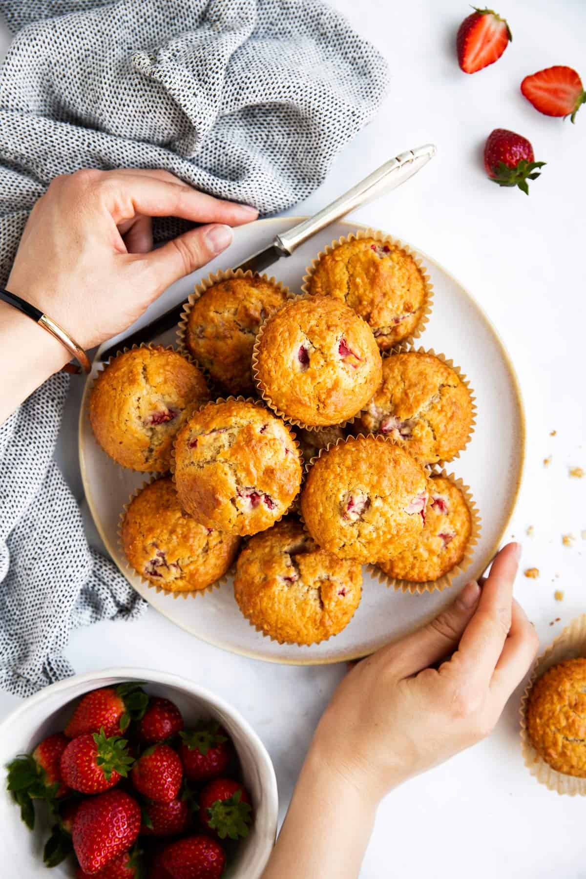 female hands holding a plate with strawberry oat muffins