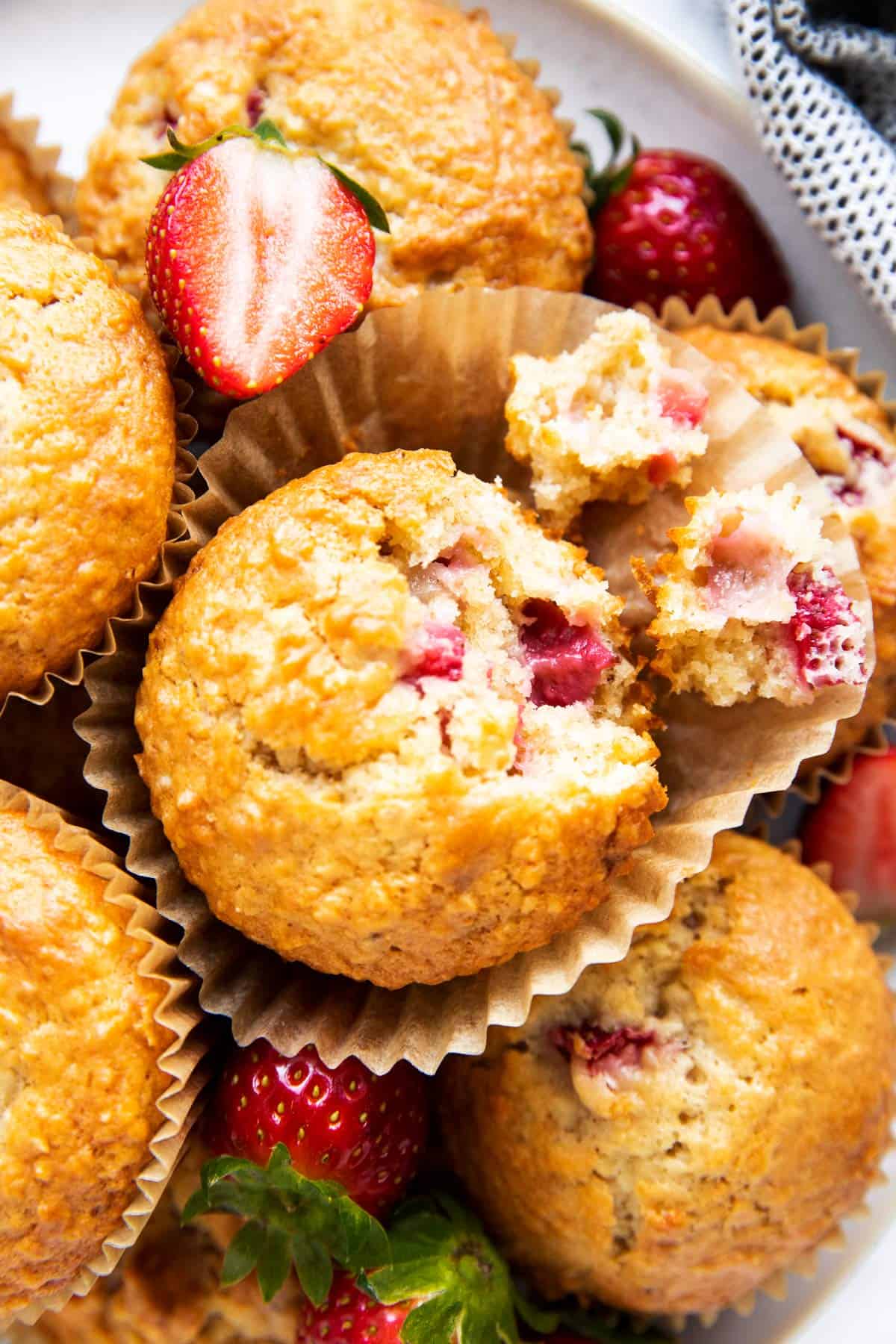 close up photo of a pile of strawberry muffins, one broken apart