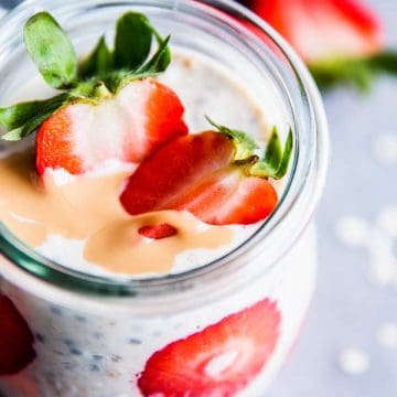 Strawberry peanut butter overnight oats in a glass jar with sliced strawberries