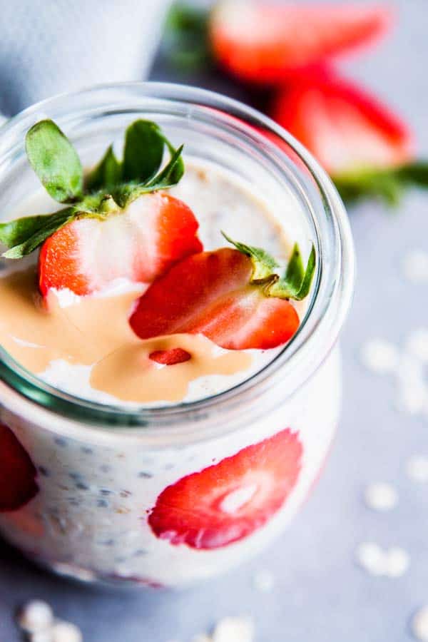 Strawberry peanut butter overnight oats in a glass jar with sliced strawberries