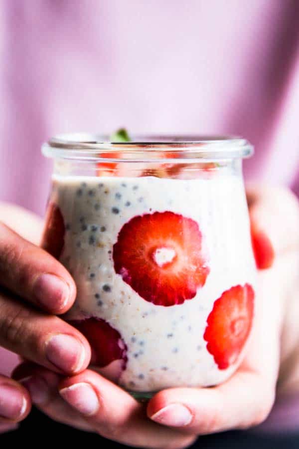 woman holding a jar of strawberry peanut butter overnight oats