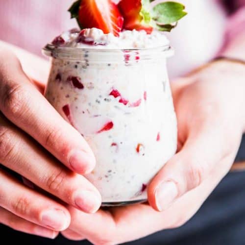 Woman holding a jar of vanilla strawberry overnight oats.