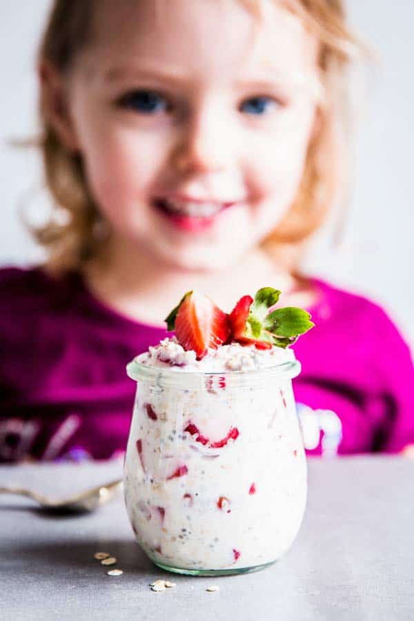 Girl with a jar of vanilla strawberry overnight oats.