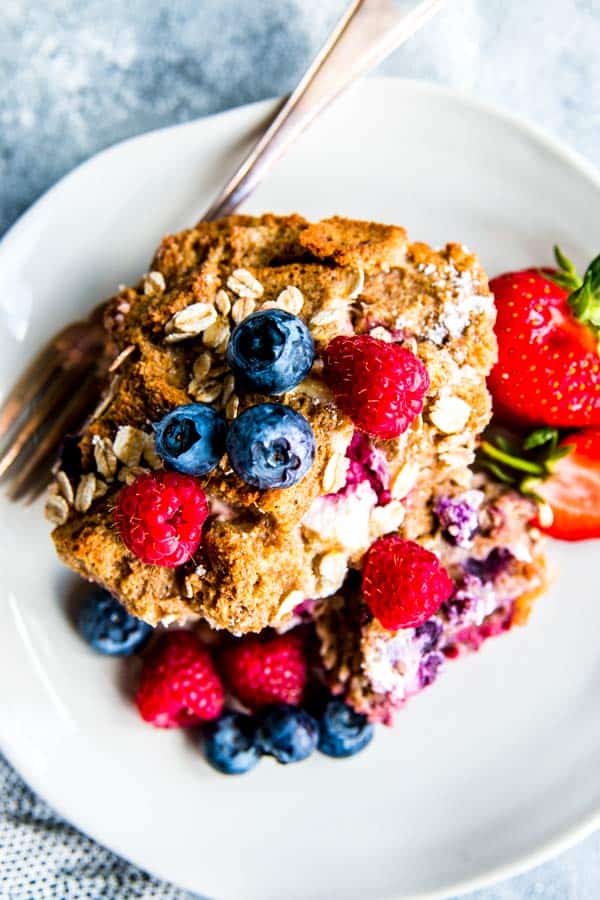 berry French toast bake with fresh berries and a fork on a white plate