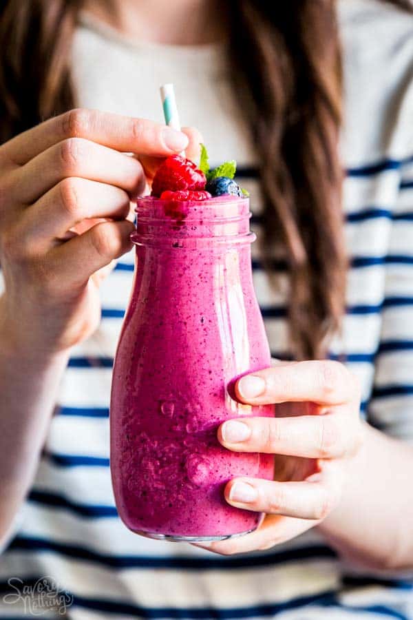 woman holding a bottle of berry smoothie