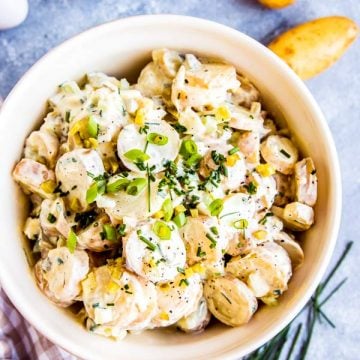 cream greek potato salad in a bowl with ingredients around it