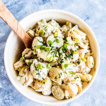 greek yogurt potato salad in a large bowl with a wooden spoon