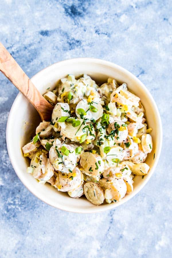 greek yogurt potato salad in a large bowl with a wooden spoon