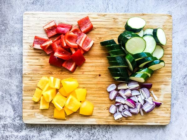 sliced vegetables on a wooden cutting board for greek chicken kabobs