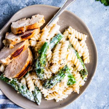 Chicken Asparagus Pasta on a light plate with a fork and some herbs