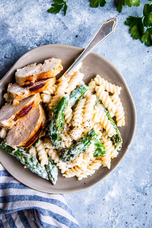 Chicken Asparagus Pasta on a light plate with a fork and some herbs