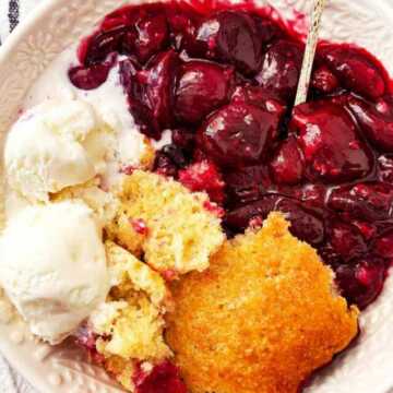 overhead view of cherry cobbler in white bowl with ice cream