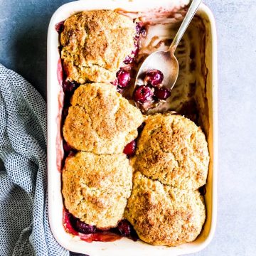 fresh cherry cobbler in a casserole dish with a spoon