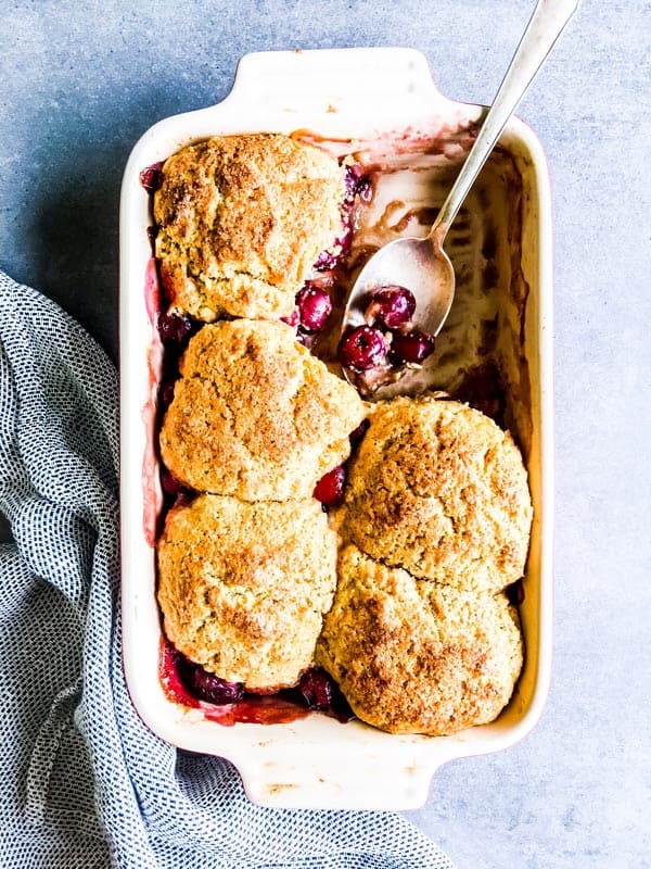 fresh cherry cobbler in a casserole dish with a spoon