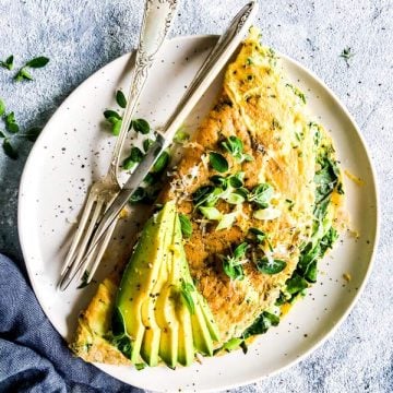 green goddess omelette on a white plate with herbs and avocado