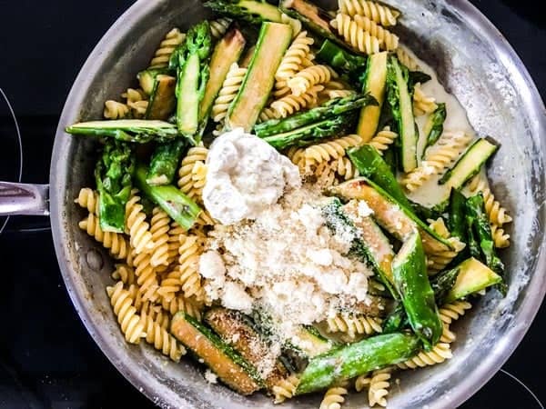 cheese and asparagus and pasta in creamy sauce in a skillet
